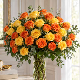 Orange and yellow roses in a tall clear glass vase