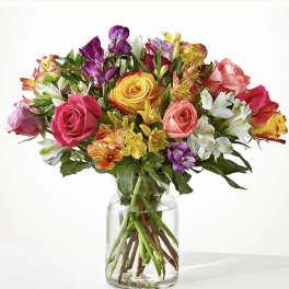 Mixed bouquet of colorful roses and alstroemeria in a clear glass vase