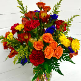Colorful bouquet of roses, carnations, and daisies in a glass vase