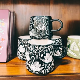 Stacked patterned ceramic mugs on a wooden shelf