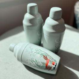 Three mint-colored bottles with floral mushroom artwork