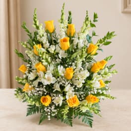 Yellow roses and white flowers arranged in a low vase