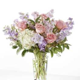 Pink roses and lavender flowers in a clear glass vase