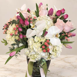 Pink roses, white orchids, and hydrangeas in a black vase