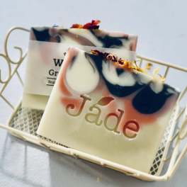 Two decorative soap bars with pink and black swirls in a small cream metal basket