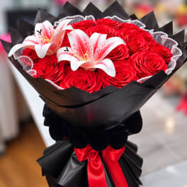 Bouquet of red roses with two white lilies in black wrap