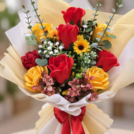 Bouquet of red and yellow flowers wrapped in cream paper with a red ribbon