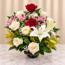 Bouquet of red and white roses with lilies in a black vase