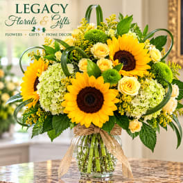Sunflower and rose arrangement in a glass vase with a burlap ribbon