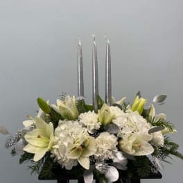 White lilies and hydrangeas arranged with three silver candles