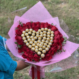 Heart-shaped bouquet of red roses and gold-wrapped chocolates in pink paper