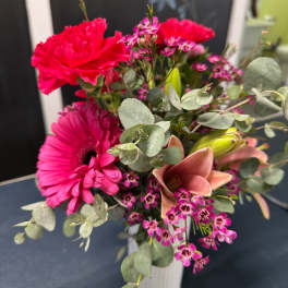 Pink bouquet with gerbera daisy, carnations, and lilies in a white vase
