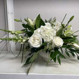 White roses and lilies arranged in a white vase
