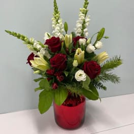 Red and white floral arrangement in a red glass vase