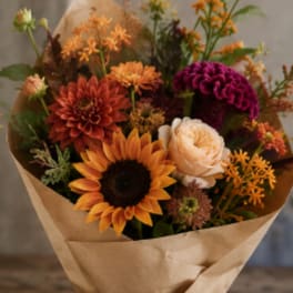 Bouquet of orange, peach, and purple flowers wrapped in kraft paper