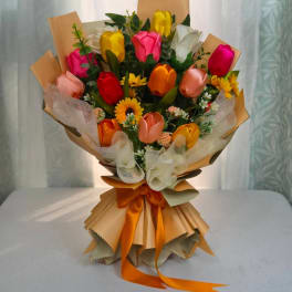Bouquet of multicolored tulips with sunflowers wrapped in tan paper