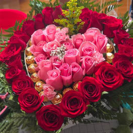 Heart-shaped rose arrangement with pink and red roses and chocolates