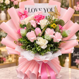 Pink and white rose bouquet wrapped in pink paper with a "I LOVE YOU" card