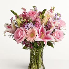 Pink roses and lilies arranged in a clear glass vase