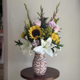 Mixed bouquet with sunflowers and white lilies in a patterned vase