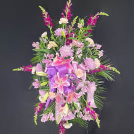 Pink and purple funeral spray with lilies and ribbon on an easel