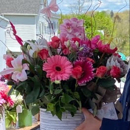 Pink and white mixed flower arrangement in a striped container