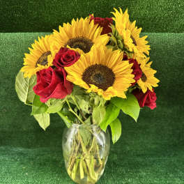 Sunflowers and red roses arranged in a clear glass vase