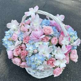 Basket of pink and blue flowers with a white handle