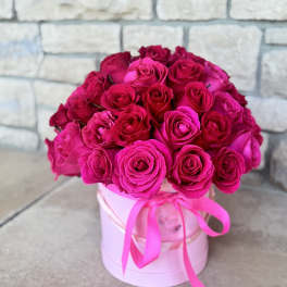 Bouquet of hot pink roses in a pink hat box with ribbon
