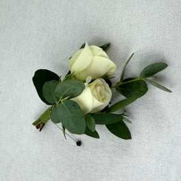 Two white rose buds with greenery on a fabric background
