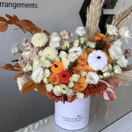 Mixed bouquet in a white hatbox with orange and white flowers and dried grasses
