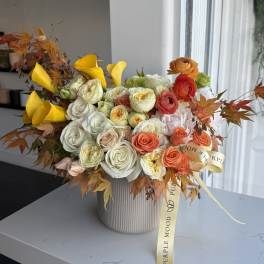 Mixed bouquet of roses, calla lilies, and autumn leaves in a ribbed vase