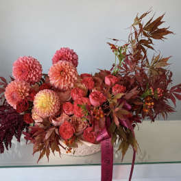 Pink and peach floral arrangement with roses and dahlias in a white container