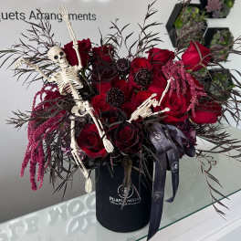 Red roses in a black box with small skeleton decorations