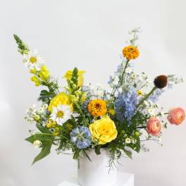 Mixed bouquet in a white vase with yellow, blue, and white flowers