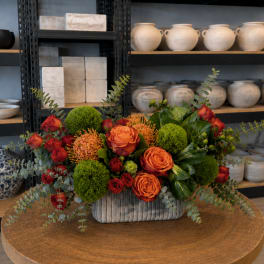 Orange and red rose arrangement in a ribbed rectangular vase