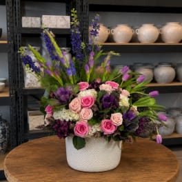 Pink and purple mixed flower arrangement in a white textured vase