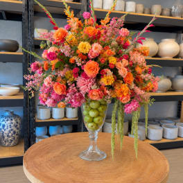 Colorful flower arrangement in a clear glass vase filled with green apples