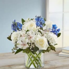 White and blue mixed bouquet in a clear glass vase
