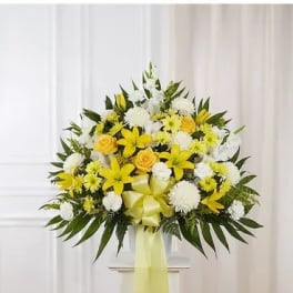 Yellow and white floral standing spray with a ribbon bow