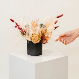 Dried floral arrangement in a black vase with red and cream accents