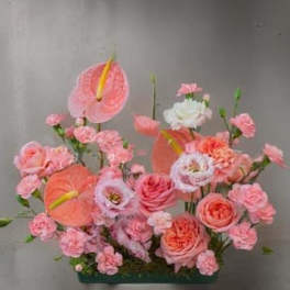 Pink floral arrangement with anthuriums, roses, and carnations in a low container