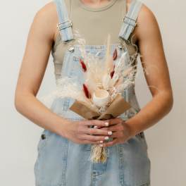 Person holding a small dried bouquet with a candle