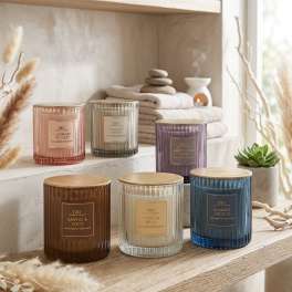 Assorted scented candles in ribbed glass jars on a wooden shelf