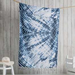 Blue and white patterned textile hanging on a rope against a wood wall