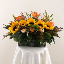 Sunflowers and orange lilies arranged in a rectangular vase