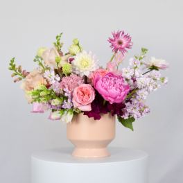 Pink and white mixed flower arrangement in a peach vase