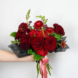 Hand-tied bouquet of red flowers with a pink ribbon