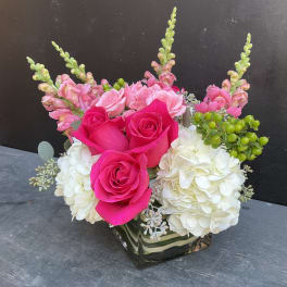 Pink roses and white hydrangeas arranged in a square glass vase