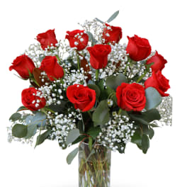 Red roses arranged in a clear glass vase with white baby's breath